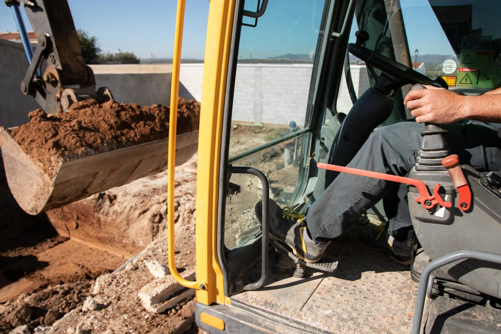 Construction worker operating an excavator to dig soil at a work site.