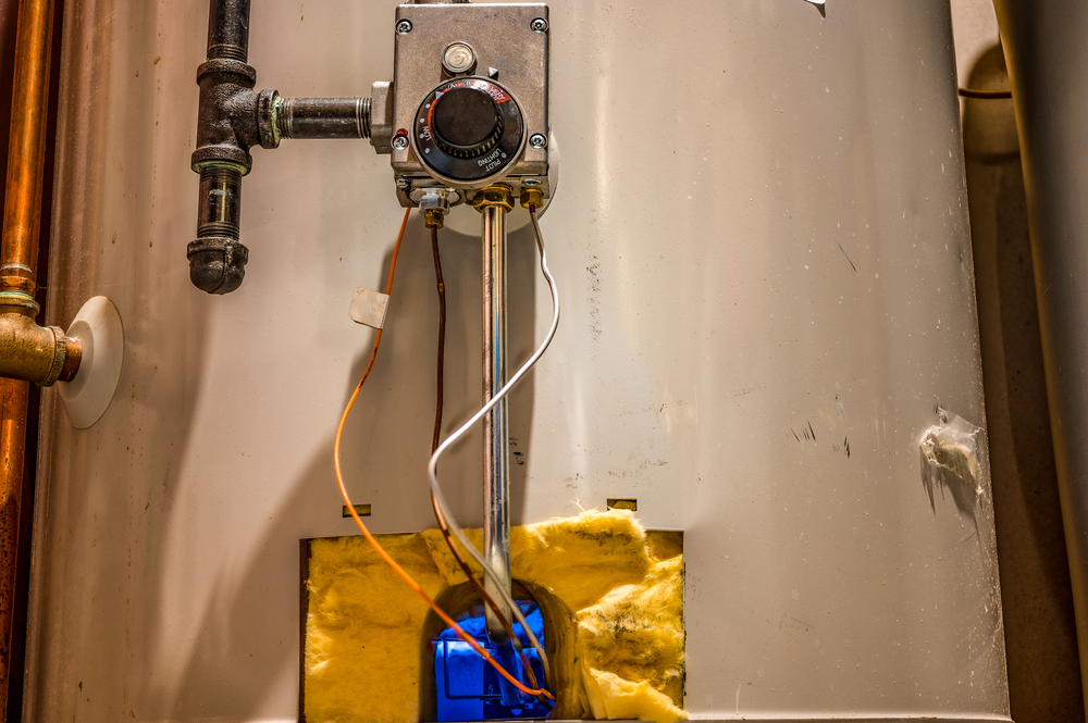 Hot water heater pilot light and burner visible with base plate removed Hot water heater maintenance and safety check that pilot is working
