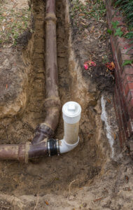 New PVC clean out installed in trench, attached to old ceramic clay pipes on sewer line
