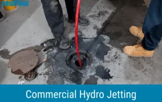 Technicians performing commercial hydro jetting with high-pressure hose to clean sewer line and remove blockages