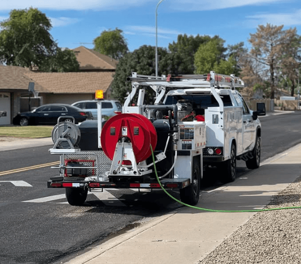 Professional hydro jetting truck with hose reel and high-pressure equipment parked on street for sewer line cleaning service