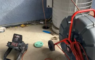 Professional sewer camera inspection equipment with monitor and cable reel set up next to a home drain access point.