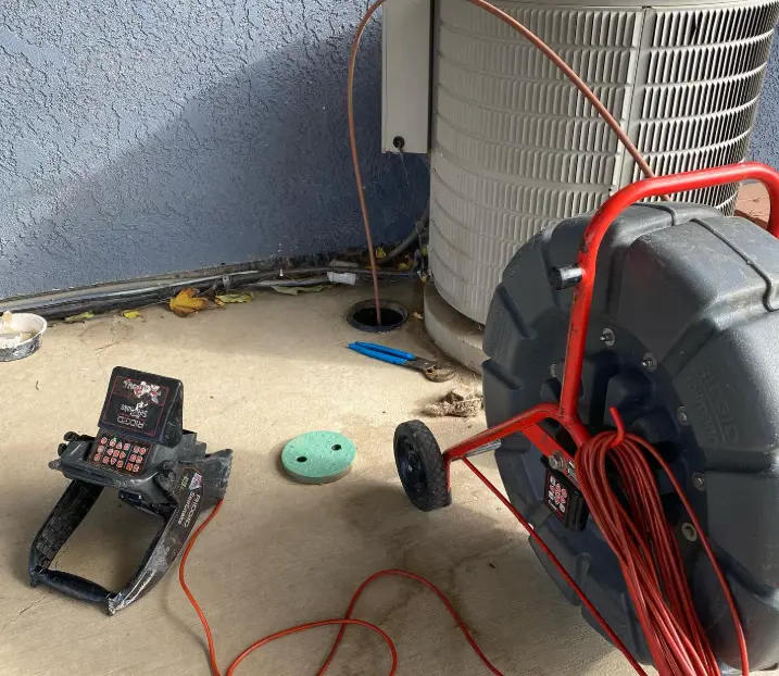 Professional sewer camera inspection equipment with monitor and cable reel set up next to a home drain access point.