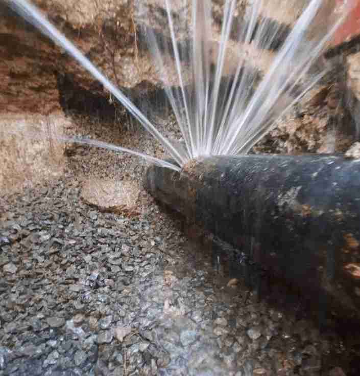 water-pipe-leak-detection-los-angeles Close-up of a leaking underground water pipe spraying water, showing a burst that requires professional leak detection and repair.